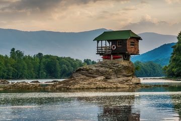 Ein Holzhaus steht in einer besonderen Lage an einem See.