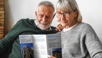 Seniorenpaar schaut sich einen Immobilienflyer an